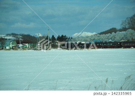 道東の雪原を走るSL冬の湿原号と冬の山並み 道東の雪原を走るSL冬の湿原号と冬の山並み 142335965