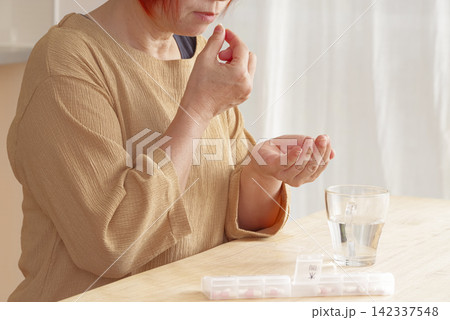 内服薬を飲もうとするシニア女性 内服薬を飲もうとするシニア女性 142337548