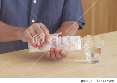 薬ケースを使って服薬管理をする男性 薬ケースを使って服薬管理をする男性 142337566