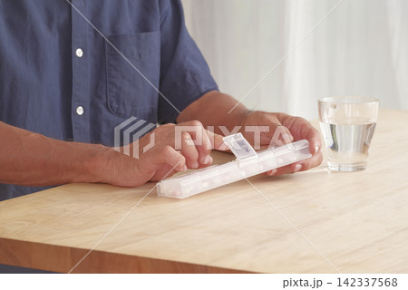 薬ケースを使って服薬管理をする男性 142337568