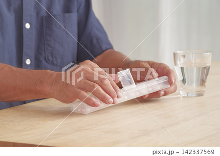 薬ケースを使って服薬管理をする男性 薬ケースを使って服薬管理をする男性 142337569