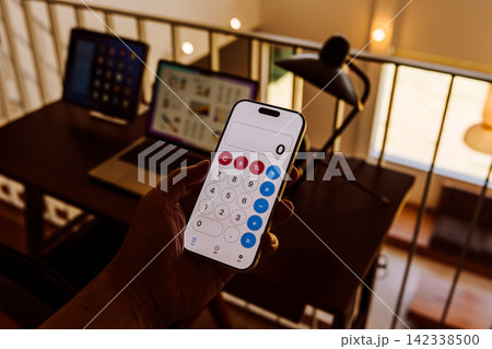 スマートフォンで電卓アプリを使う手 142338500