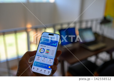 スマートフォンで資産管理アプリを見る手 142338512