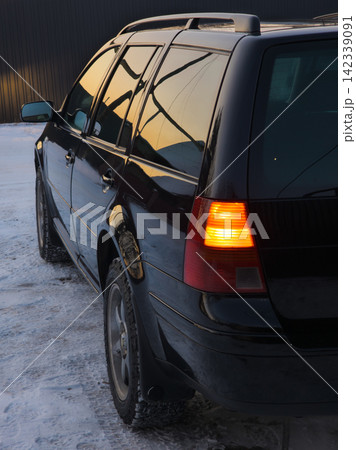 Black Station Wagon Parked on Snowy Ground at Sunset Black Station Wagon Parked on Snowy Ground at Sunset 142339091