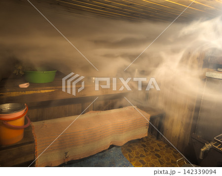 Interior of a Steamy Sauna with Wooden Benches and Accessories 142339094