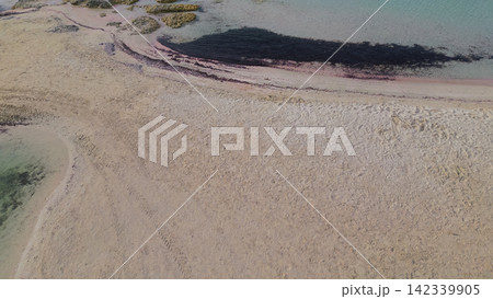 Aerial perspective of Balos Bay reveals a sandy beach with clear turquoise waters and visible patches of algae along the shoreline, emphasizing the natural beauty of the coastal landscape in Crete Aerial perspective of Balos Bay reveals a sandy beach with clear turquoise waters and visible patches of algae along the shoreline, emphasizing the natural beauty of the coastal landscape in Crete 142339905
