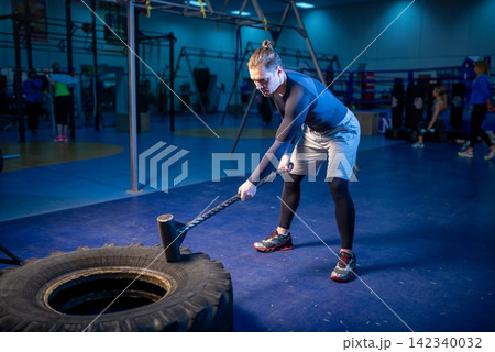Man hitting a large heavy tire with a sledgehammer 142340032