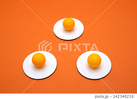 Three yellow balls on white circles on an orange background Three yellow balls on white circles on an orange background 142340218