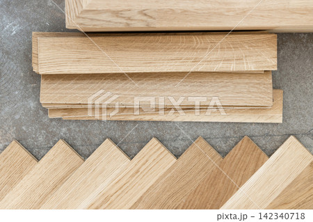 Beige parquet planks on concrete floor during herringbone hardwood flooring installation Beige parquet planks on concrete floor during herringbone hardwood flooring installation 142340718