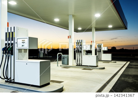 Modern gas station pumps illuminated at dusk with a colorful sky Modern gas station pumps illuminated at dusk with a colorful sky 142341367