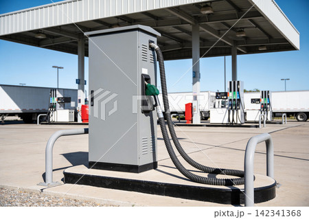 Gas station fuel pump with hoses and trucks in the background on a sunny day Gas station fuel pump with hoses and trucks in the background on a sunny day 142341368