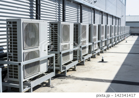 Row of outdoor air conditioning units installed on a rooftop next to a corrugated metal building Row of outdoor air conditioning units installed on a rooftop next to a corrugated metal building 142341417
