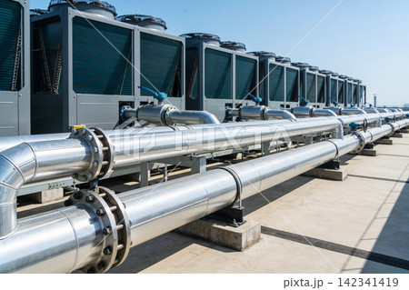 Industrial HVAC units and large pipes on a rooftop under a clear blue sky 142341419