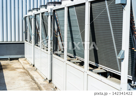 Row of industrial air conditioning units on a rooftop under bright sunlight Row of industrial air conditioning units on a rooftop under bright sunlight 142341422