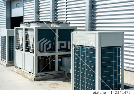 Industrial air conditioning units on a rooftop with a corrugated metal building background Industrial air conditioning units on a rooftop with a corrugated metal building background 142341473