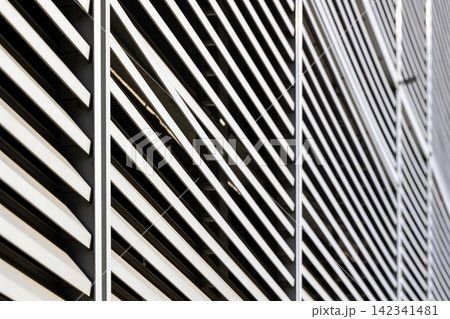 Modern architectural facade with diagonal lines and shadows creating a striking pattern Modern architectural facade with diagonal lines and shadows creating a striking pattern 142341481