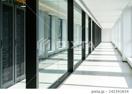 Modern data center hallway with server racks and glass walls casting shadows 142341654