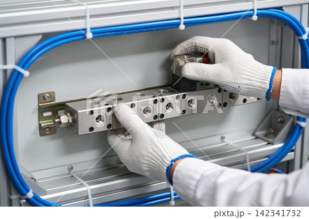 Technician installing pneumatic solenoid valve manifold in industrial automation system Technician installing pneumatic solenoid valve manifold in industrial automation system 142341732