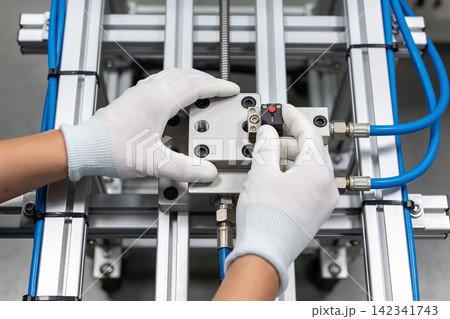 Technician wearing white gloves carefully assembling a complex industrial machine component Technician wearing white gloves carefully assembling a complex industrial machine component 142341743
