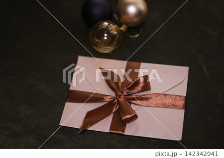 Pink envelope with bronze ribbon and bow on dark background Pink envelope with bronze ribbon and bow on dark background 142342041