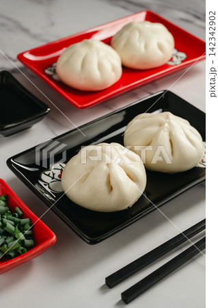Steamed bao buns with chopped green onion served on black plate Steamed bao buns with chopped green onion served on black plate 142342902