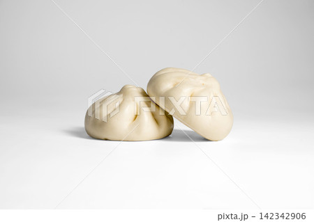 Soft steamed bao buns with pleated tops on bright background Soft steamed bao buns with pleated tops on bright background 142342906