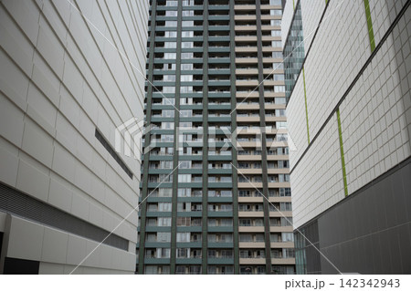 近代的な高層マンションと両脇のビルが織りなす、幾何学的でシンメトリーな都市景観 近代的な高層マンションと両脇のビルが織りなす、幾何学的でシンメトリーな都市景観 142342943
