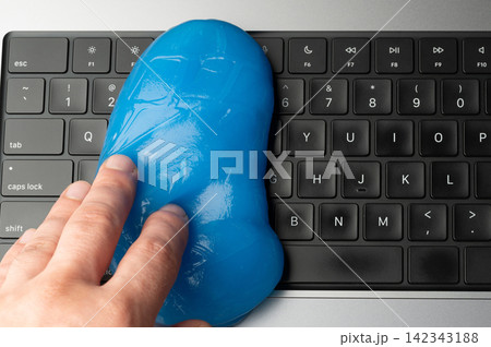 Cleaning a keyboard with blue cleaning gel and a hand Cleaning a keyboard with blue cleaning gel and a hand 142343188