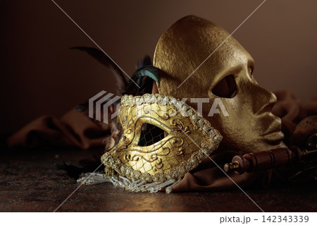 Golden carnival masks on a brown background. 142343339