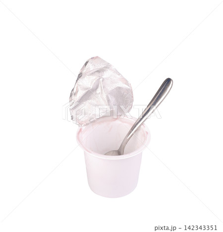 An opened yogurt container with a spoon inside. An opened yogurt container with a spoon inside. 142343351