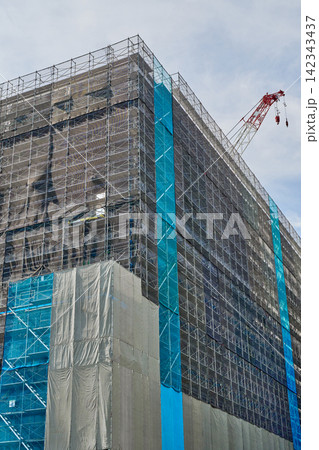 建設が進む高層ビルの外観と青空へ向かって伸びる大型クレーン 建設が進む高層ビルの外観と青空へ向かって伸びる大型クレーン 142343437