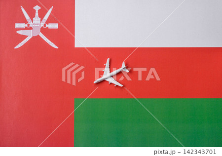 An airplane on the Omani flag as a conceptual backdrop for travel. An airplane on the Omani flag An airplane on the Omani flag as a conceptual backdrop for travel. An airplane on the Omani flag 142343701