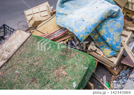 A large pile of wooden, cardboard, plastic crates and old mattress is on a garbage heap. Wooden and plastic and cardboard boxes from under berries on a garbage heap 142343869