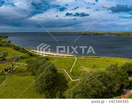 High angle wide horizontal aerial drone photograph of Lake Veere coastline, green ramparts, beach path, wind turbines, and dramatic storm sky in Veere, Zeeland, Netherlands on summer day High angle wide horizontal aerial drone photograph of Lake Veere coastline, green ramparts, beach path, wind turbines, and dramatic storm sky in Veere, Zeeland, Netherlands on summer day 142344385