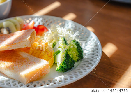 温かい光が差す洋食朝食プレートのクローズアップと木製テーブル 温かい光が差す洋食朝食プレートのクローズアップと木製テーブル 142344773