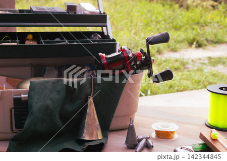 Fishing tackle box filled with various angling gear, including reels, lines, lures, weights, and tools, preparing for an outdoor hobby and vacation activity Fishing tackle box filled with various angling gear, including reels, lines, lures, weights, and tools, preparing for an outdoor hobby and vacation activity 142344845