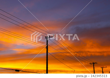 夕焼け空に浮かび上がる電柱と電線のシルエット 142345313