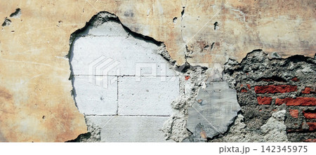 A damaged wall revealing concrete blocks and red brickwork texture. 142345975