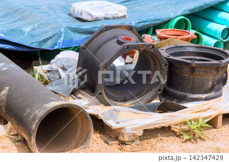 Wooden pallet at construction site holds several pipes, fittings, tools, materials. 142347429