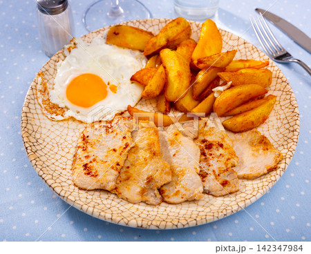 Plate with prepared food pork chop with potatoes and fried egg 142347984