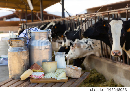 Fresh dairy products on table on background of cows in stall Fresh dairy products on table on background of cows in stall 142348028