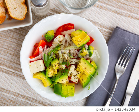 Tomato, avocado, onion salad served on table Tomato, avocado, onion salad served on table 142348034