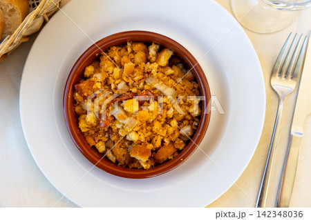 Migas pastoriles, fried crumbled bread with chorizo and bacon served in clay cazuela Migas pastoriles, fried crumbled bread with chorizo and bacon served in clay cazuela 142348036