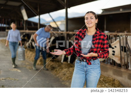 Portrait of positive young woman farmer in cowhouse Portrait of positive young woman farmer in cowhouse 142348253