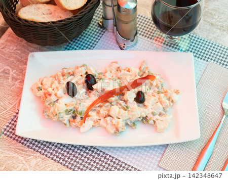 Russian salad of boiled vegetables and canned tuna with black olives 142348647