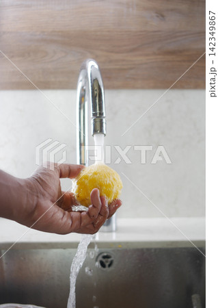 Hand holding a yellow sponge under running water Hand holding a yellow sponge under running water 142349867