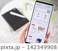 スマートフォンで求人サイトをチェックする写真 (スマホ画面内はオリジナルのサンプル画像) 142349908