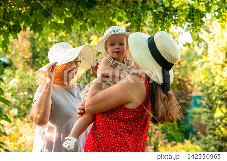 Three Generations Wearing Sun Hats In Summer Garden Three Generations Wearing Sun Hats In Summer Garden 142350965