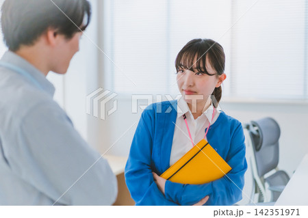 同僚男性に不満そうなジト目を向ける職場の女性スタッフ 同僚男性に不満そうなジト目を向ける職場の女性スタッフ 142351971