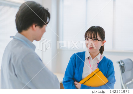 手帳を持ち同僚男性を見つめ恋心を感じる女性社員のオフィスラブ 手帳を持ち同僚男性を見つめ恋心を感じる女性社員のオフィスラブ 142351972